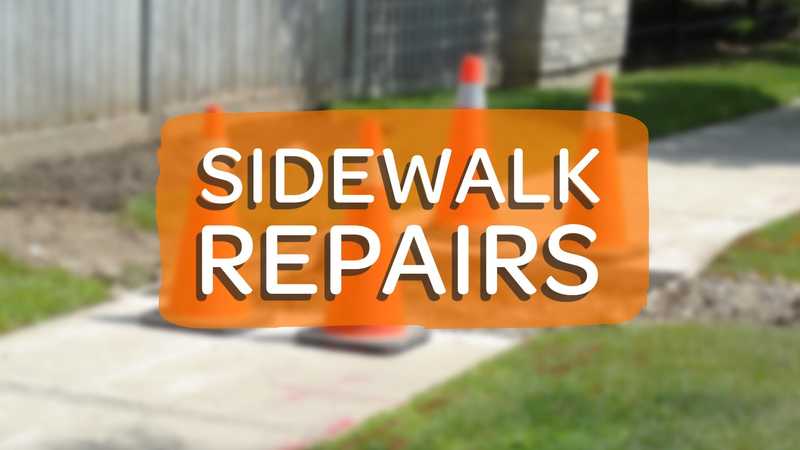 A worker’s view of orange traffic cones placed around a fresh concrete sidewalk repair, with a large "SIDEWALK REPAIRS" text overlay in a semi-transparent orange box.